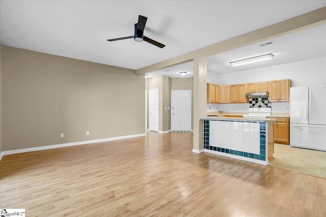 kitchen featuring open floor plan, light countertops, white appliances, and light wood-style floors