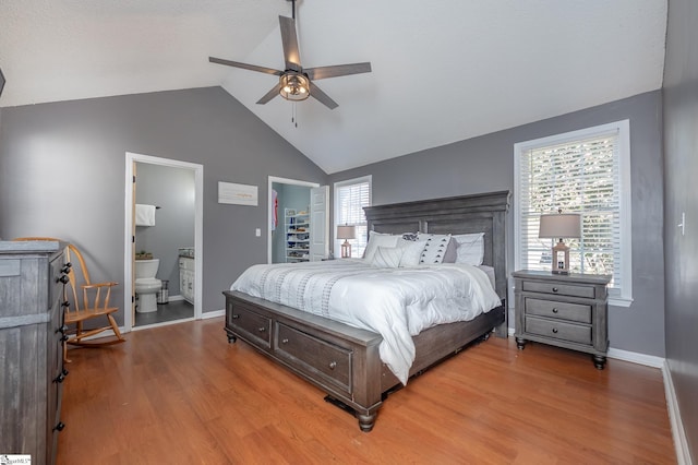 bedroom featuring vaulted ceiling, wood finished floors, a walk in closet, and ensuite bathroom