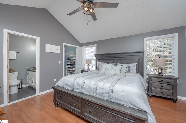 bedroom with lofted ceiling, a walk in closet, light wood-style flooring, and ensuite bathroom