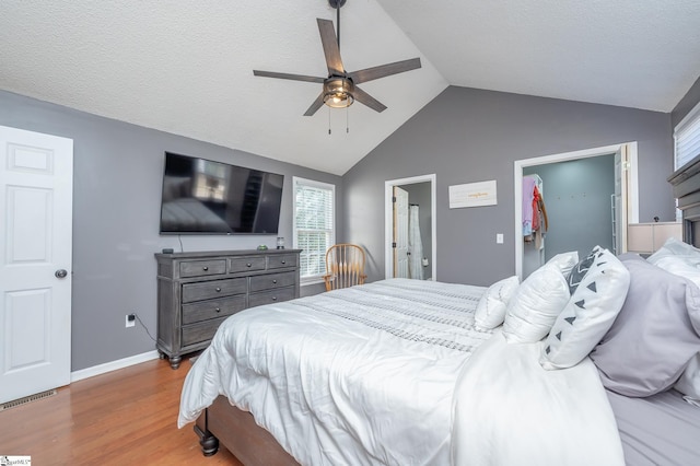 bedroom with light wood finished floors, baseboards, visible vents, a spacious closet, and vaulted ceiling