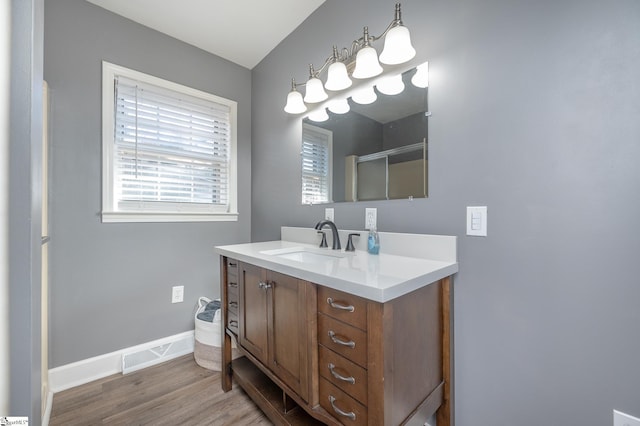 bathroom featuring baseboards, visible vents, wood finished floors, an enclosed shower, and vanity