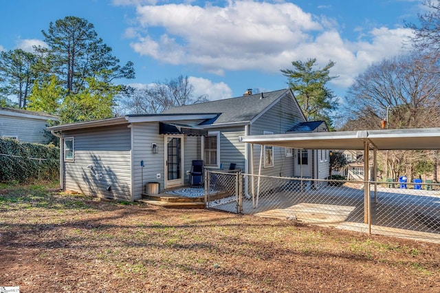 back of property with a shingled roof and fence