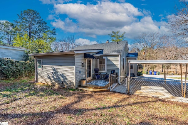 back of property with a shingled roof and fence