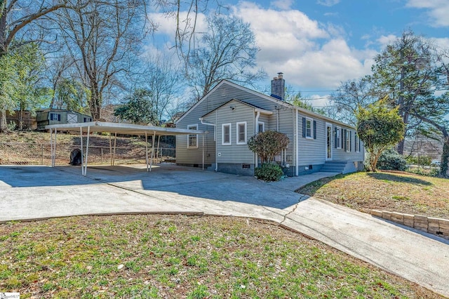 view of side of property featuring driveway, a carport, and a chimney