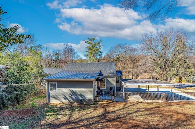 rear view of property with metal roof and a yard