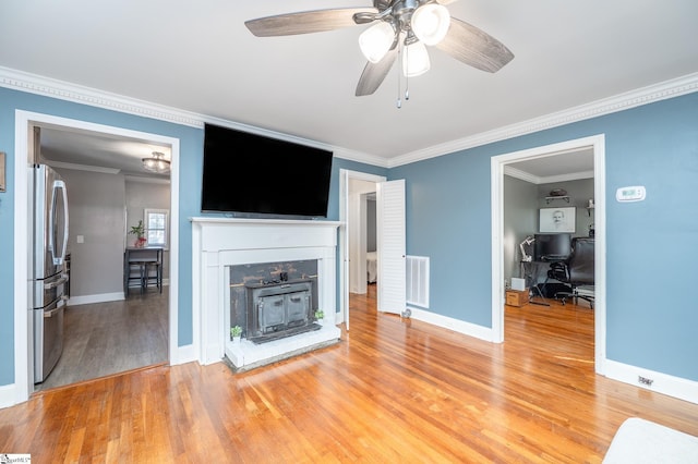 unfurnished living room with light wood finished floors, baseboards, and crown molding