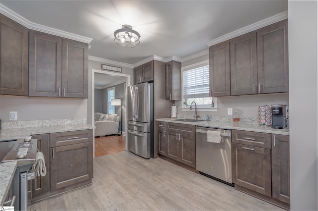 kitchen featuring stainless steel appliances, a sink, light stone counters, and dark brown cabinetry