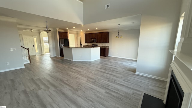 kitchen featuring stainless steel microwave, open floor plan, a center island, decorative light fixtures, and black refrigerator with ice dispenser