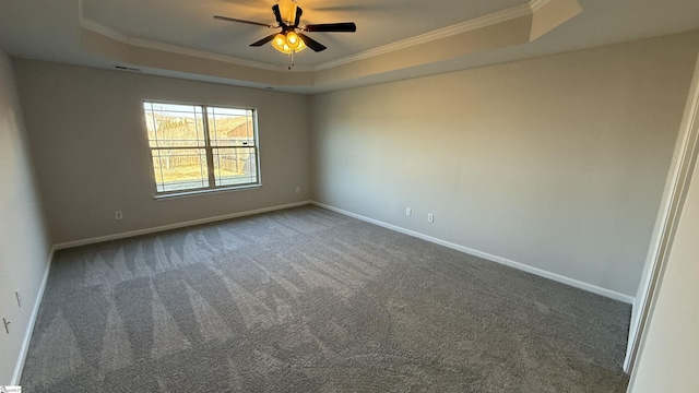 empty room featuring baseboards, a ceiling fan, a tray ceiling, dark colored carpet, and crown molding