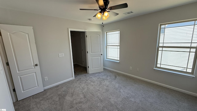 unfurnished bedroom featuring carpet floors, a ceiling fan, visible vents, and baseboards