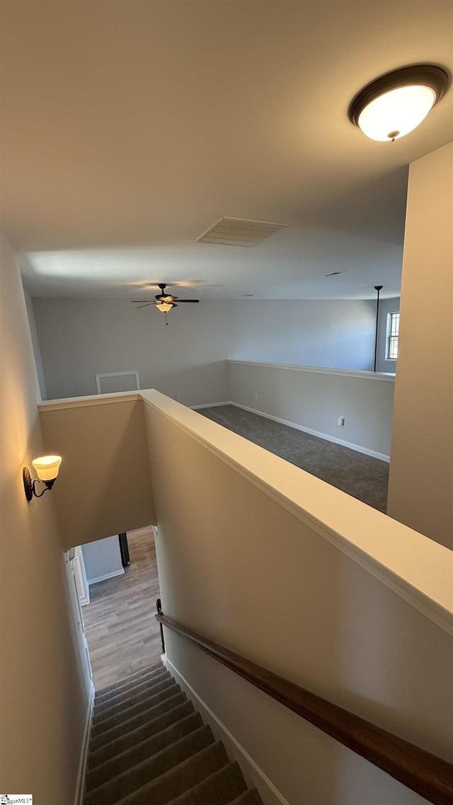 stairway with ceiling fan, visible vents, and wood finished floors