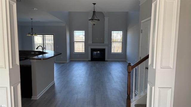 unfurnished living room featuring stairway, plenty of natural light, a fireplace with flush hearth, and dark wood finished floors