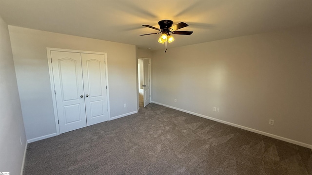 unfurnished bedroom featuring dark colored carpet, a closet, and baseboards