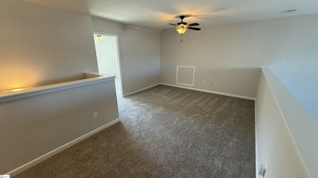 unfurnished room with ceiling fan, dark carpet, visible vents, and baseboards