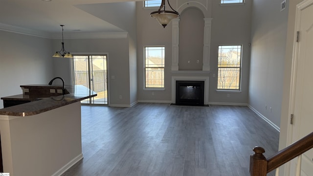 unfurnished living room with dark wood finished floors, ornamental molding, a fireplace with flush hearth, and visible vents