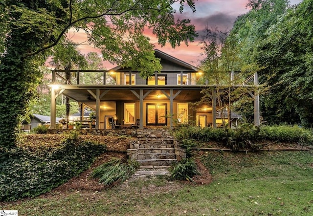 back of property at dusk featuring a yard