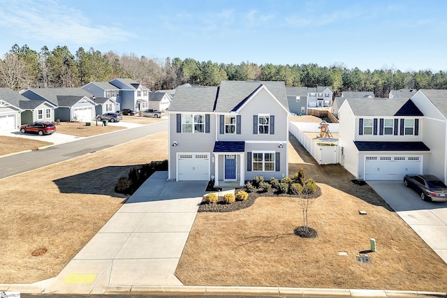 traditional-style house with a residential view, an attached garage, concrete driveway, and fence