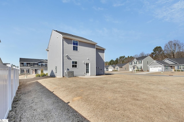 rear view of house featuring central air condition unit, a residential view, a yard, and fence