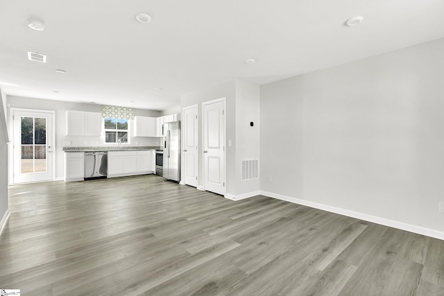 unfurnished living room featuring visible vents, baseboards, and light wood-style floors