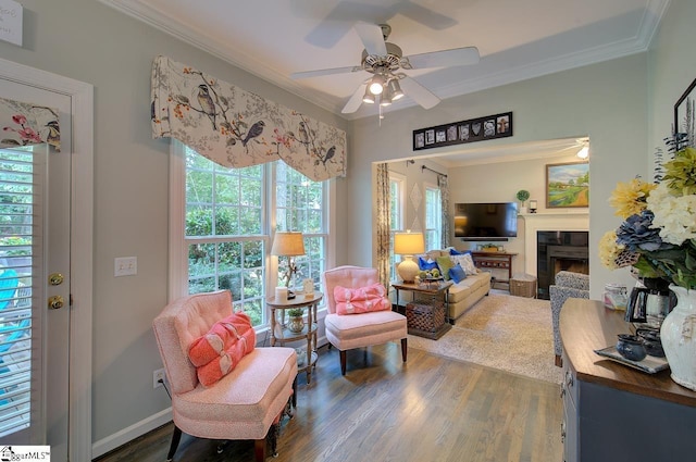 interior space with ornamental molding, dark wood-type flooring, a fireplace, and a ceiling fan