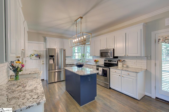 kitchen featuring a center island, white cabinets, appliances with stainless steel finishes, light stone countertops, and decorative light fixtures