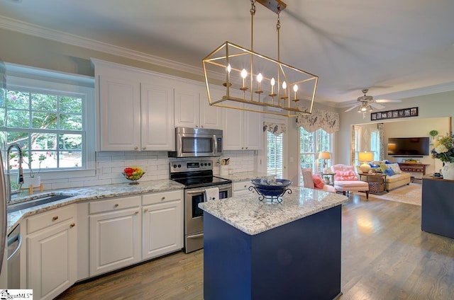 kitchen with white cabinetry, a kitchen island, appliances with stainless steel finishes, and crown molding