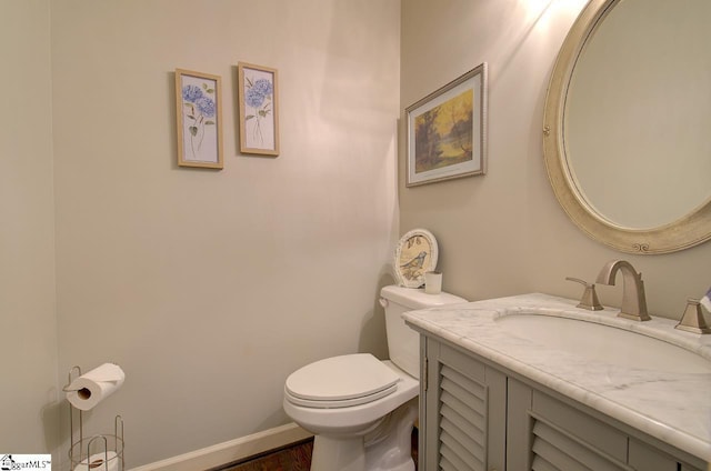 half bath with toilet, baseboards, and vanity