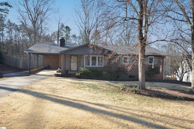 single story home with a carport, concrete driveway, brick siding, and a front yard