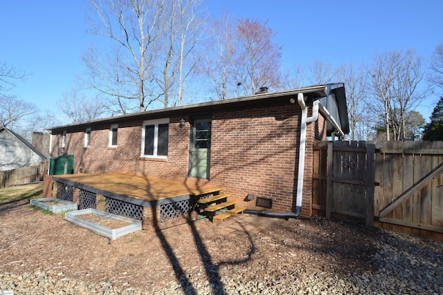 back of house with a deck, brick siding, and fence