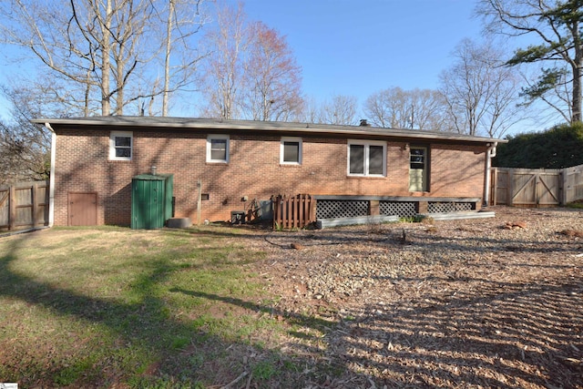 back of house with crawl space, a gate, fence, and brick siding