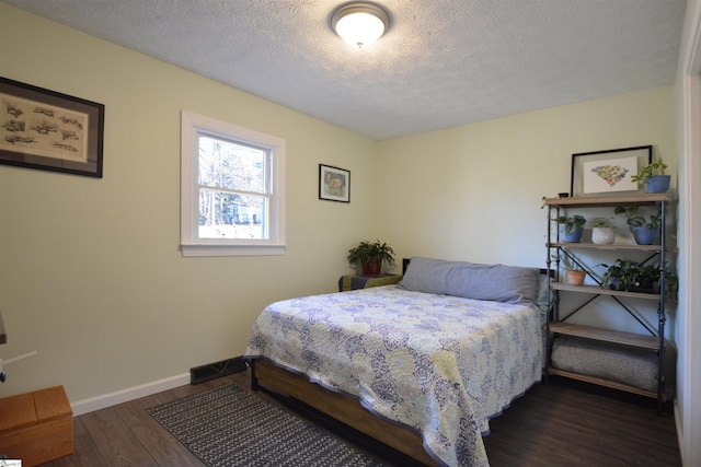 bedroom with a textured ceiling, dark wood finished floors, and baseboards