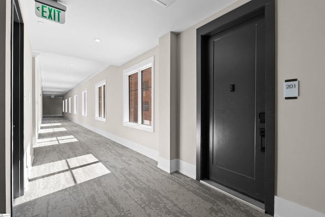 hallway featuring dark colored carpet and baseboards