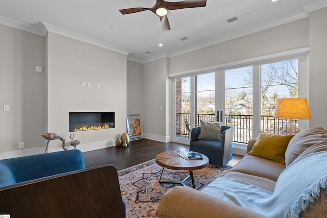 living room featuring ornamental molding, a glass covered fireplace, and a wealth of natural light