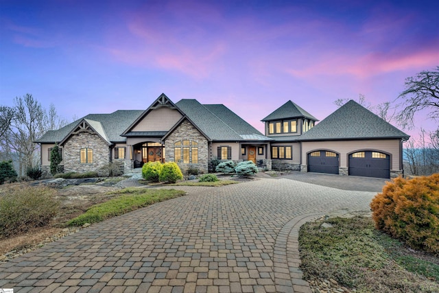 view of front of home with an attached garage, stone siding, and decorative driveway