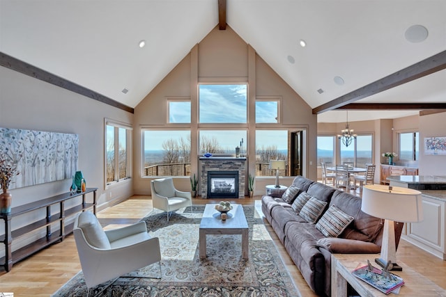 living area with a stone fireplace, a notable chandelier, visible vents, light wood-type flooring, and beam ceiling