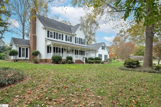 colonial inspired home with a porch, a front yard, and a chimney