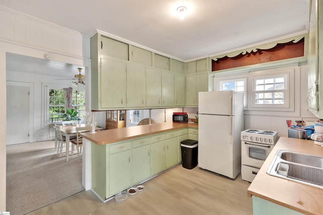 kitchen with white appliances, green cabinets, light countertops, and a sink