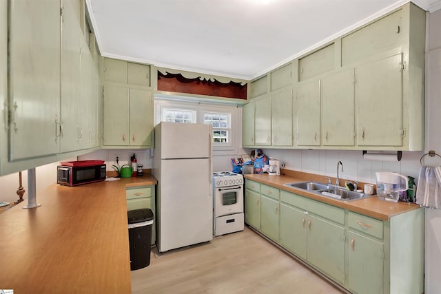 kitchen featuring white appliances, a sink, light countertops, light wood-style floors, and green cabinetry