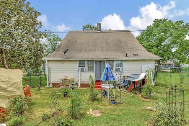 rear view of house with roof with shingles, a chimney, fence, and a yard