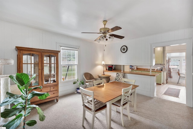 dining area featuring light carpet, cooling unit, and a ceiling fan