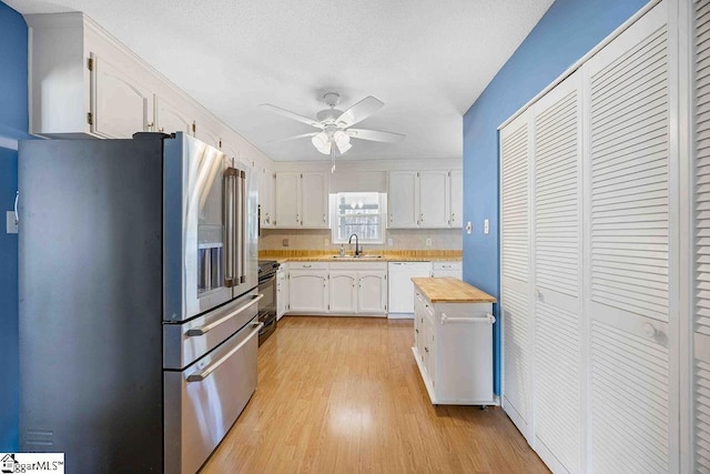 kitchen featuring white dishwasher, a sink, white cabinets, high end fridge, and range