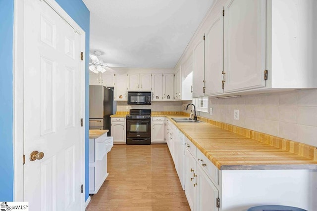 kitchen with white cabinets, black appliances, light countertops, and a sink