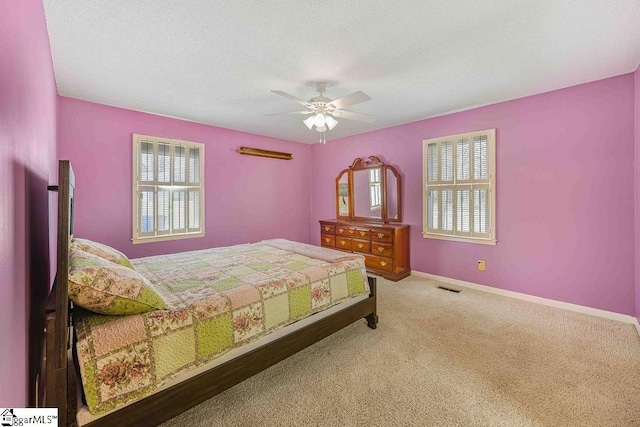 carpeted bedroom with a textured ceiling, a ceiling fan, visible vents, and baseboards