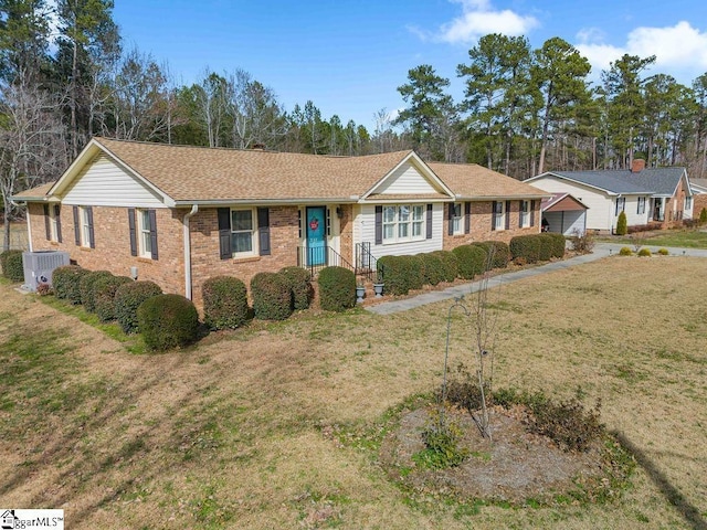 ranch-style house featuring roof with shingles, a front lawn, cooling unit, and brick siding