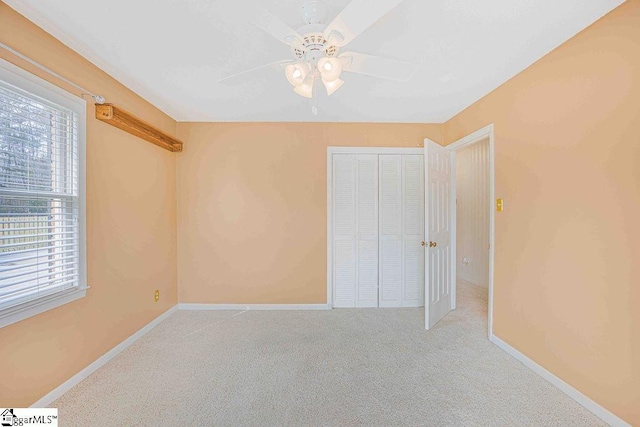 unfurnished bedroom featuring a closet, multiple windows, light carpet, and baseboards