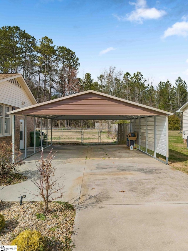 view of parking / parking lot featuring driveway, fence, and a carport