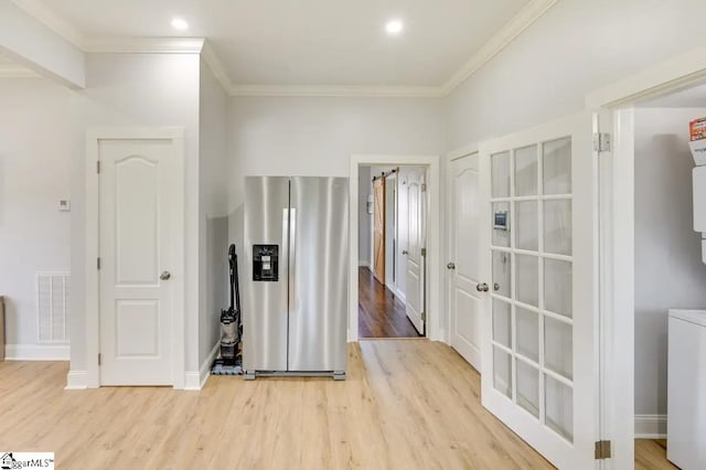 hallway featuring light wood-style flooring, visible vents, baseboards, and ornamental molding