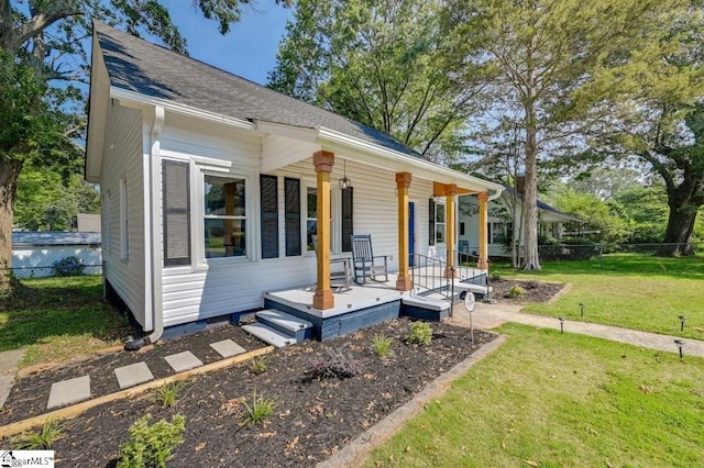 bungalow with roof with shingles, a porch, a front lawn, and fence