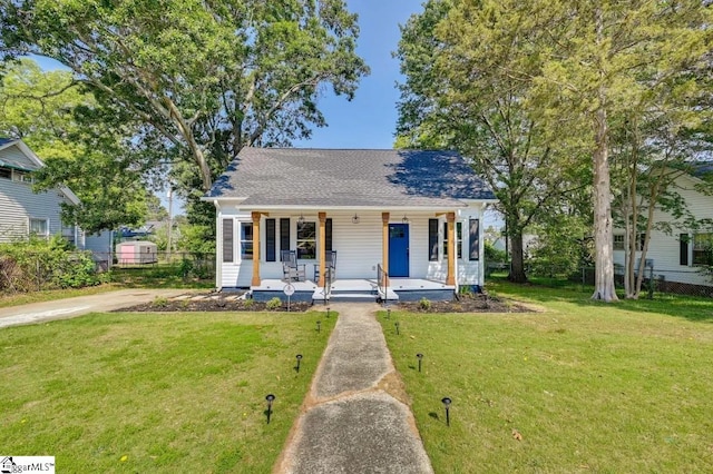 bungalow featuring covered porch, fence, and a front lawn