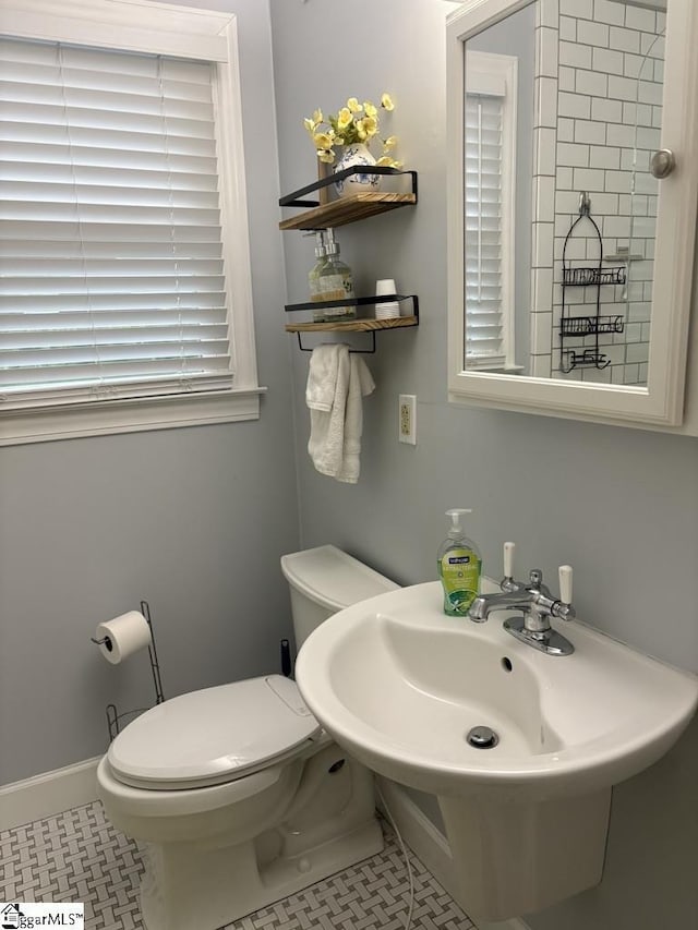 bathroom with baseboards, a sink, toilet, and tile patterned floors